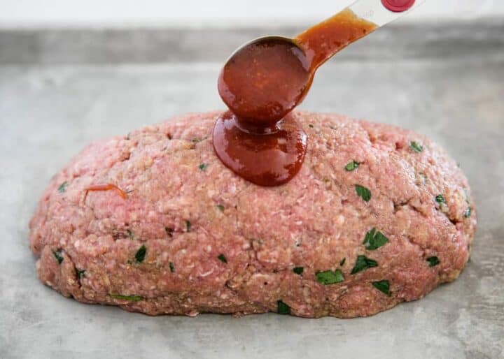 meatloaf on pan with sauce being poured over