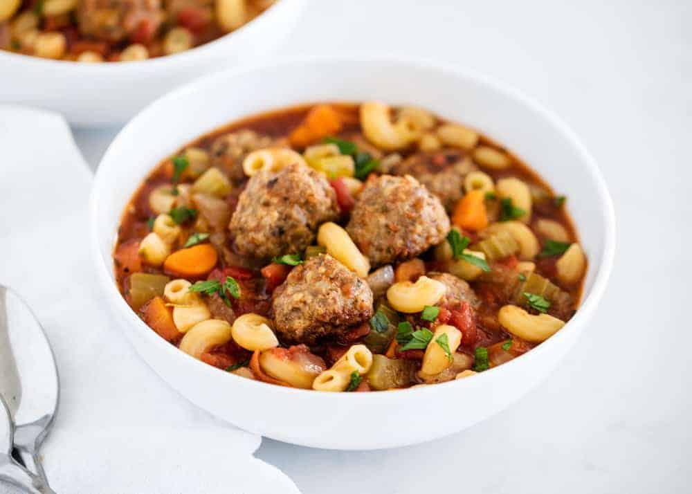 Bowl of meatball soup topped with fresh basil.