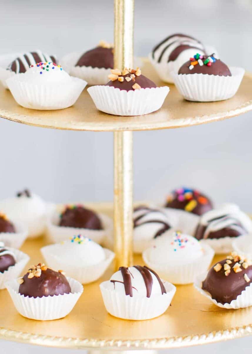 Creamy peanut butter balls covered in a sweet chocolate coating with a dash of sea salt. This delicious treat is always the first gone at a party! peanut butter balls on gold cake stand