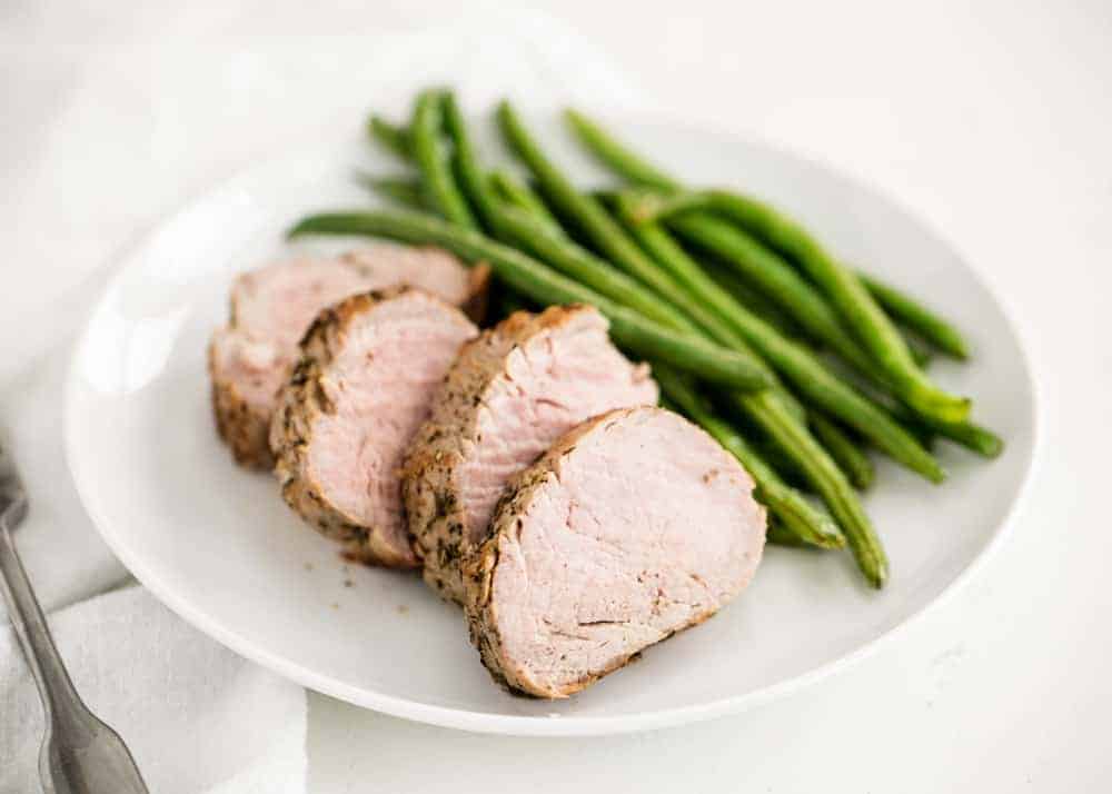 Plate with sliced pork tenderloin and green beans.