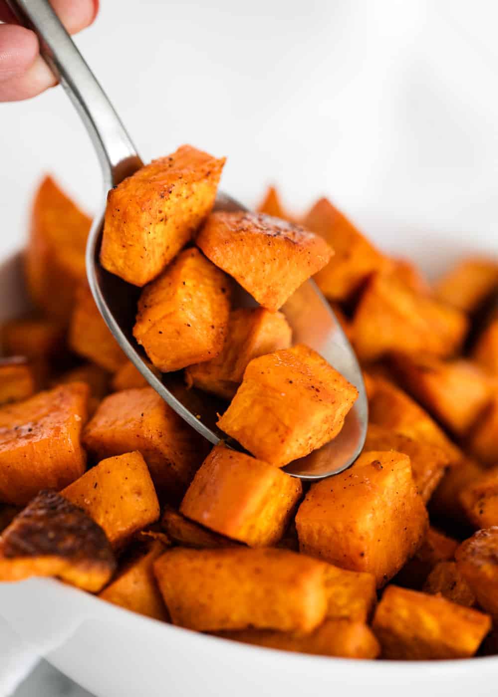Scooping up roasted sweet potatoes with a spoon.