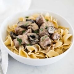 A bowl of slow cooker beef stroganoff dished into a bowl with egg noodles.