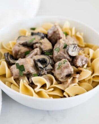 A bowl of slow cooker beef stroganoff dished into a bowl with egg noodles.
