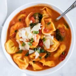 bowl of tomato tortellini soup with shaved parmesan on top