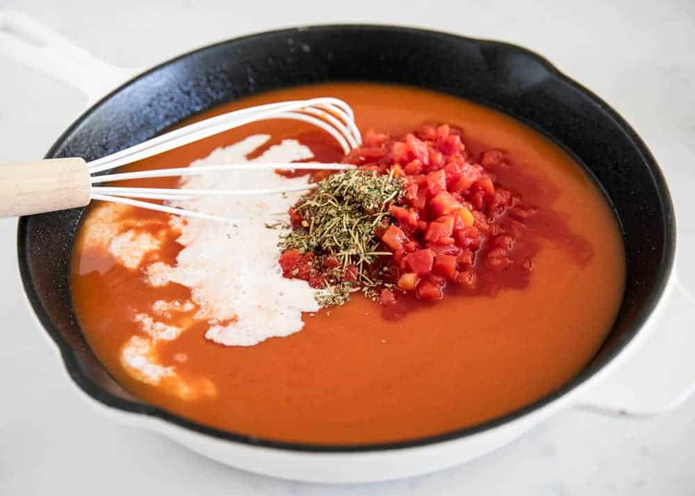 Whisking together ingredients in skillet for tomato tortellini soup.