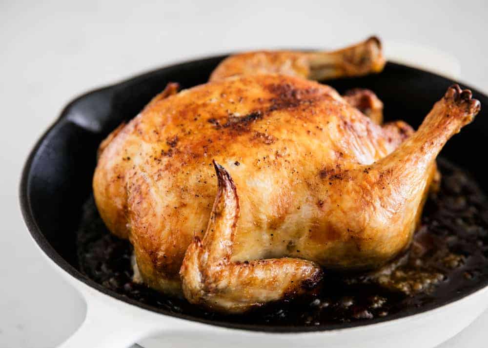 Whole roasted chicken in a cast iron skillet.