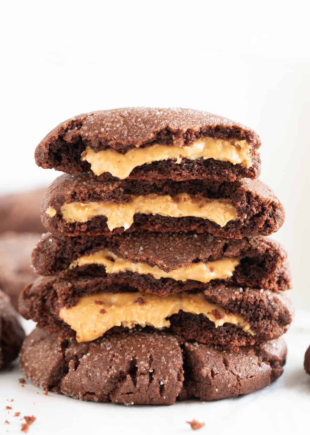 Stack of chocolate peanut butter stuffed cookies with peanut butter filling oozing out.