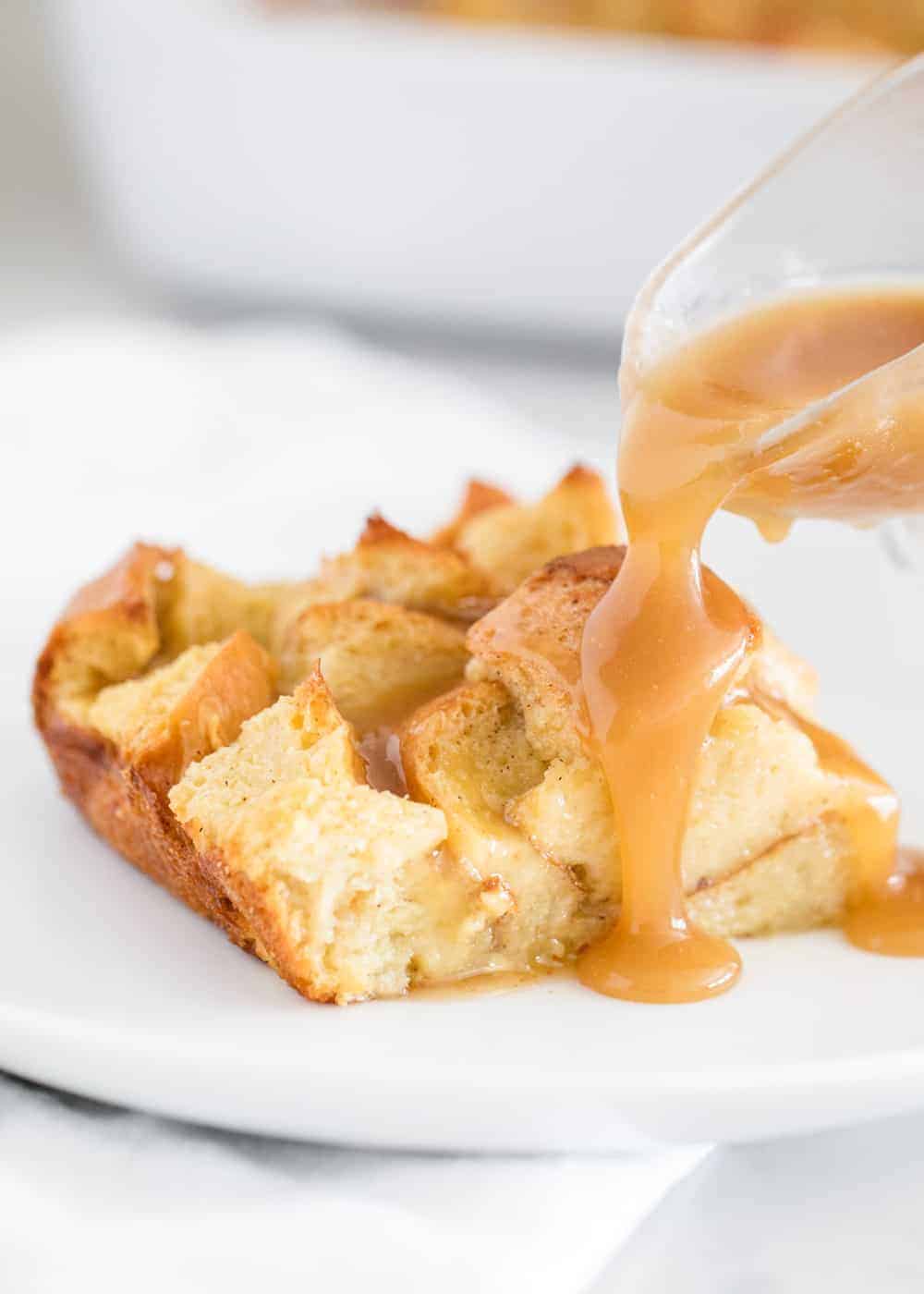 pouring caramel sauce over a slice of bread pudding 