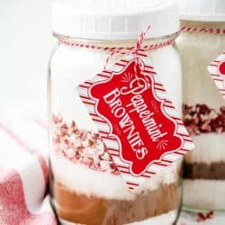 layered ingredients for peppermint brownies in a mason jar with a tag