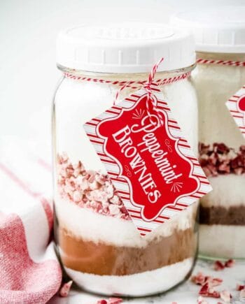 layered ingredients for peppermint brownies in a mason jar with a tag