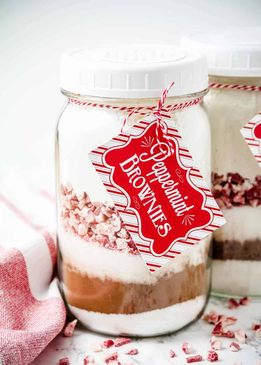 Layered ingredients for peppermint brownies in a mason jar with a tag.