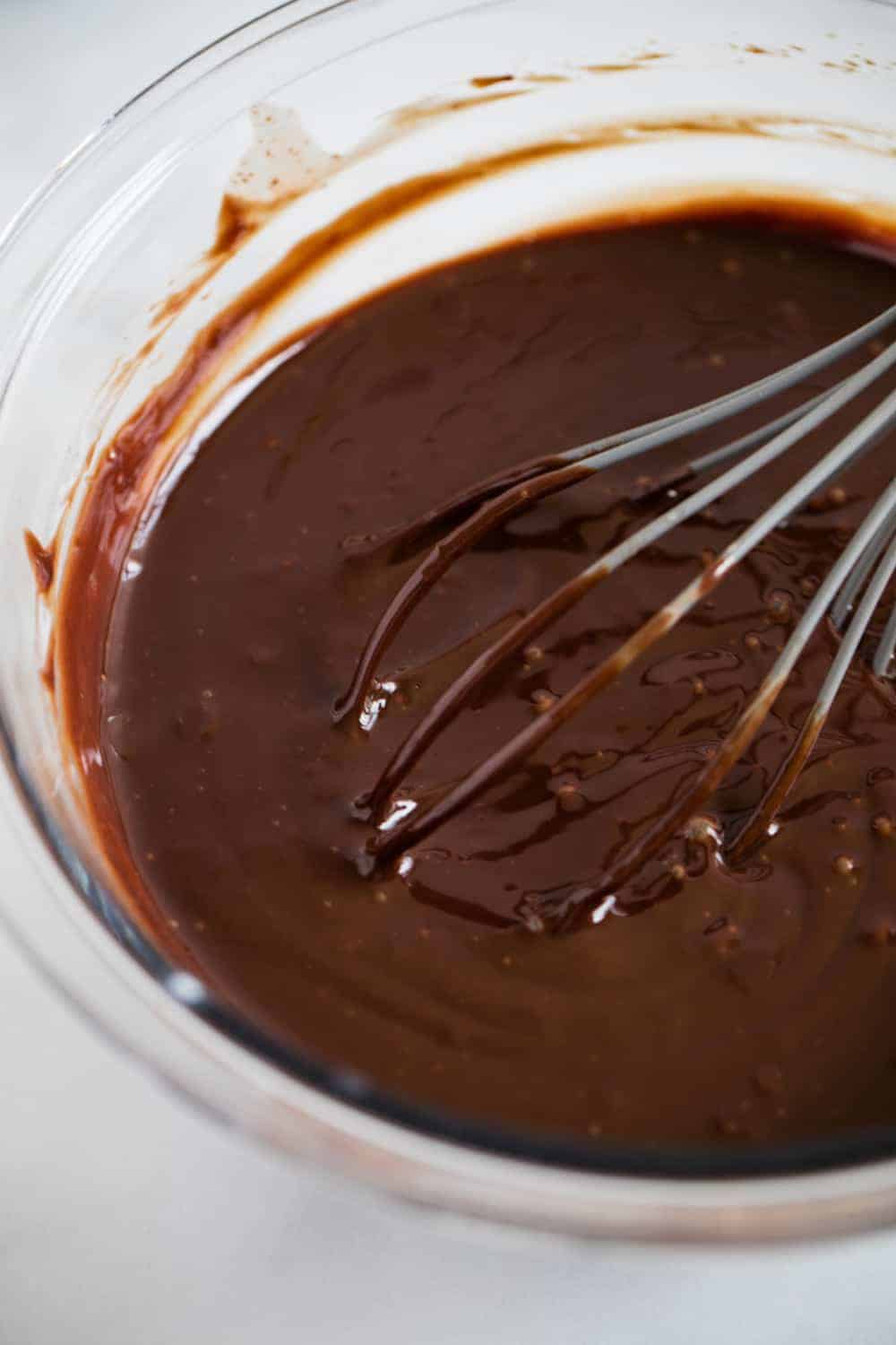 Whisking chocolate ganache in glass bowl.