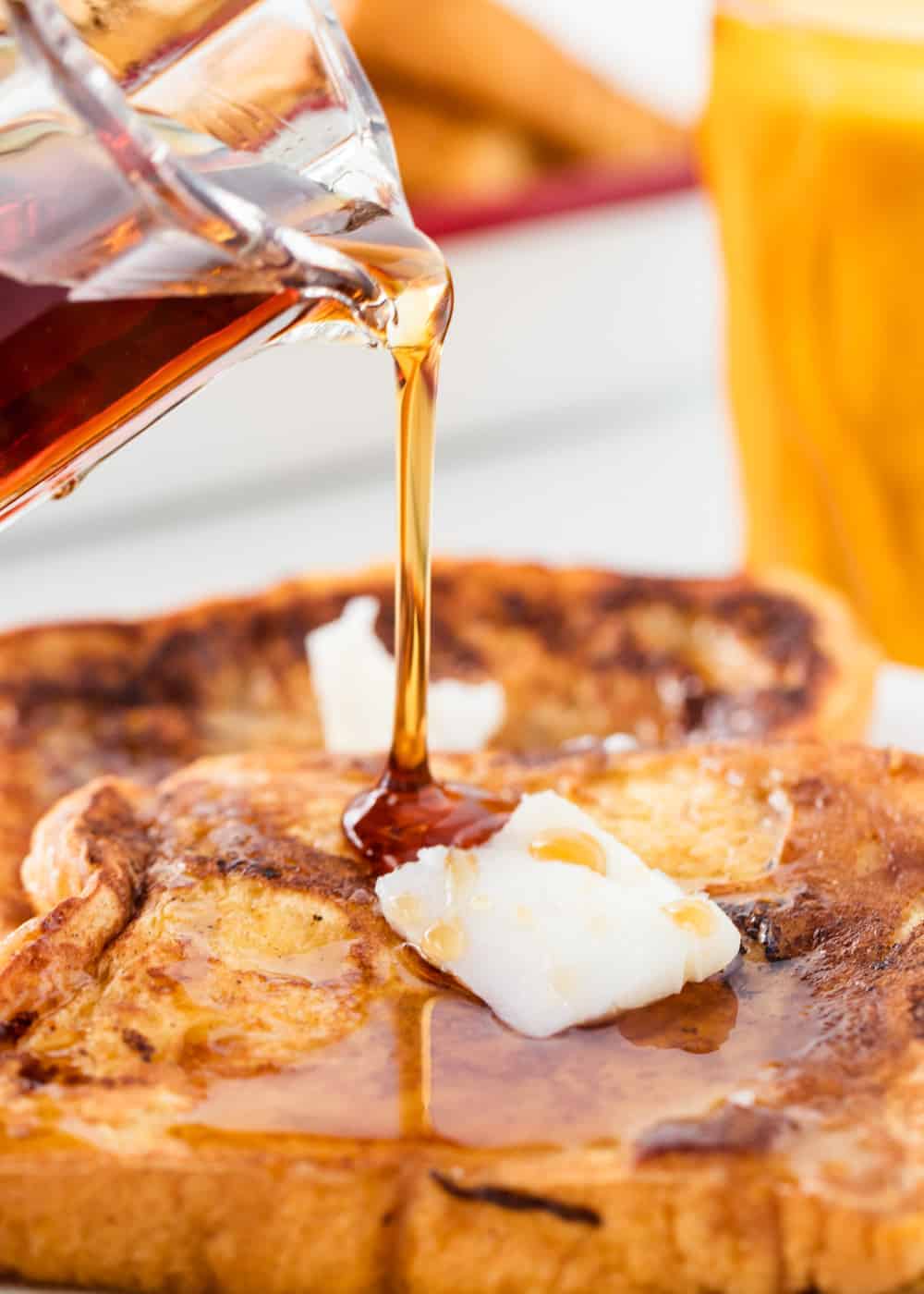 This easy eggnog french toast is the perfect recipe for your Christmas morning or holiday brunch! It's golden, rich and full of delicious eggnog flavor. Pouring syrup on top of eggnog french toast.