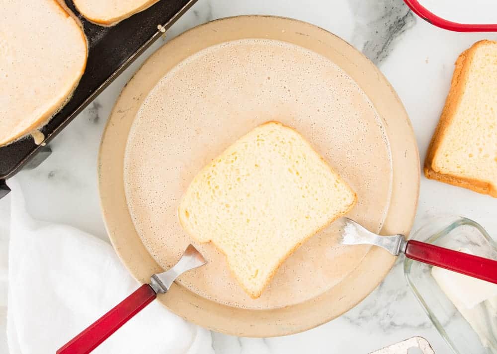 Dipping bread into eggnog mixture for eggnog french toast.