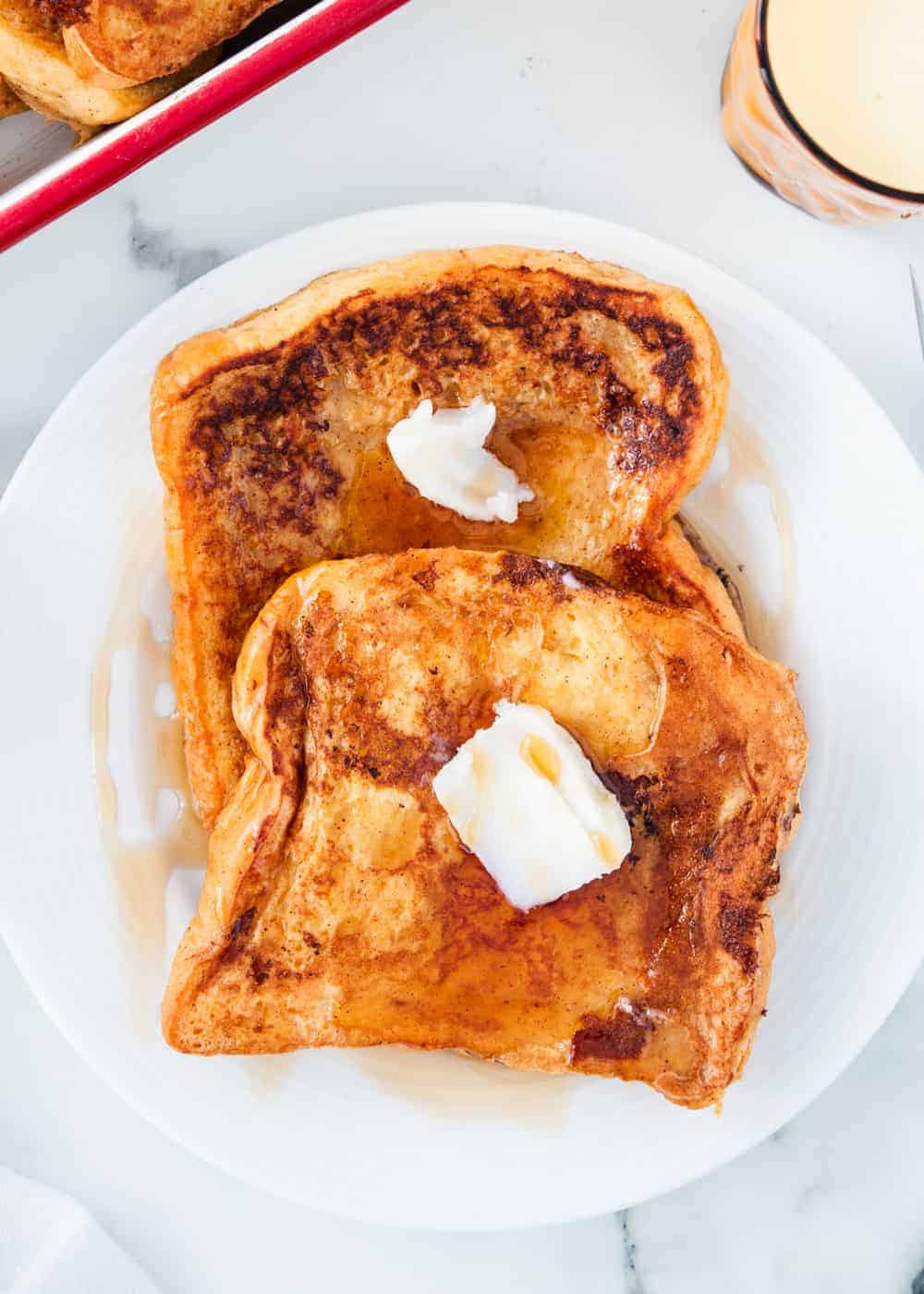 This easy eggnog french toast is the perfect recipe for your Christmas morning or holiday brunch! It's golden, rich and full of delicious eggnog flavor. Eggnog french toast on a white plate.