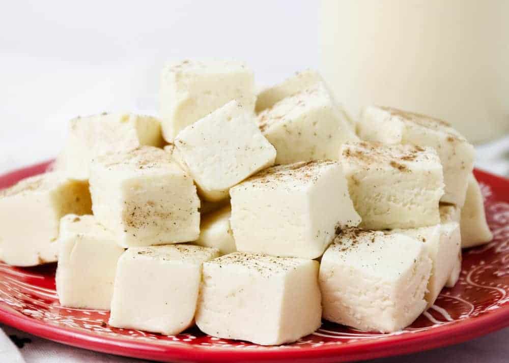 Squares of eggnog fudge on a red plate.