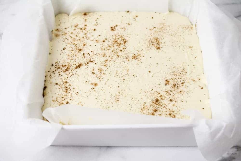 Eggnog fudge in a baking dish lined with parchment paper.