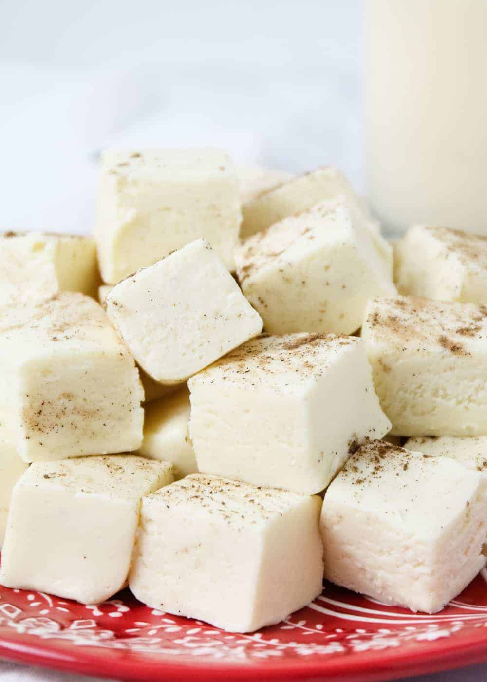 Stack of eggnog fudge on a red Christmas plate.