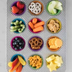muffin tin filled with different types of snacks in each muffin cup