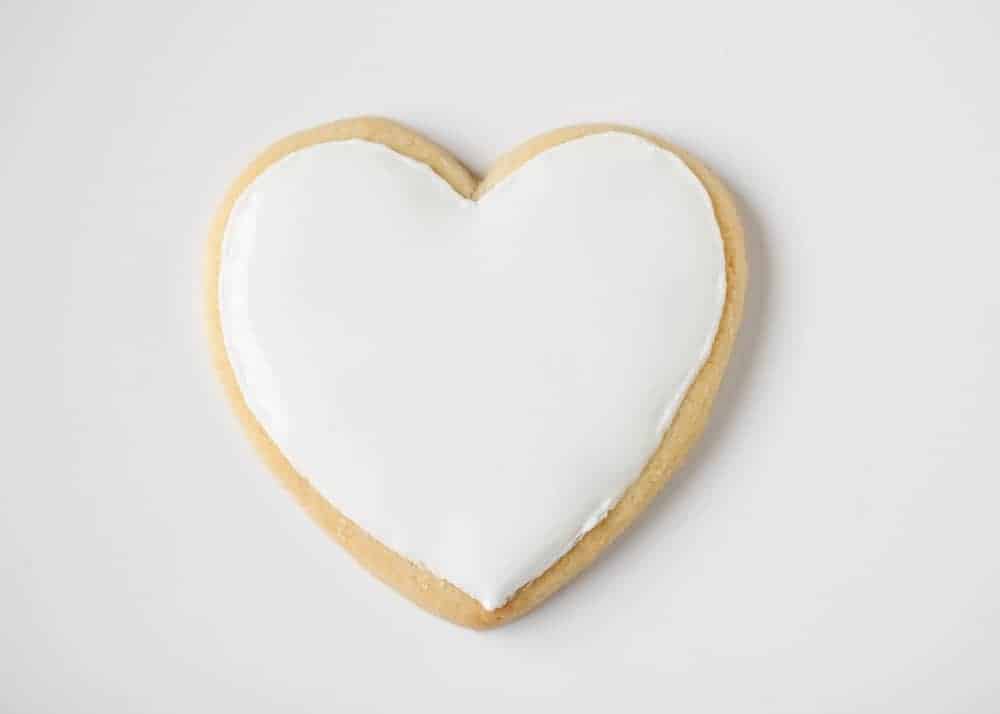 Heart shaped sugar cookie topped with white royal icing.