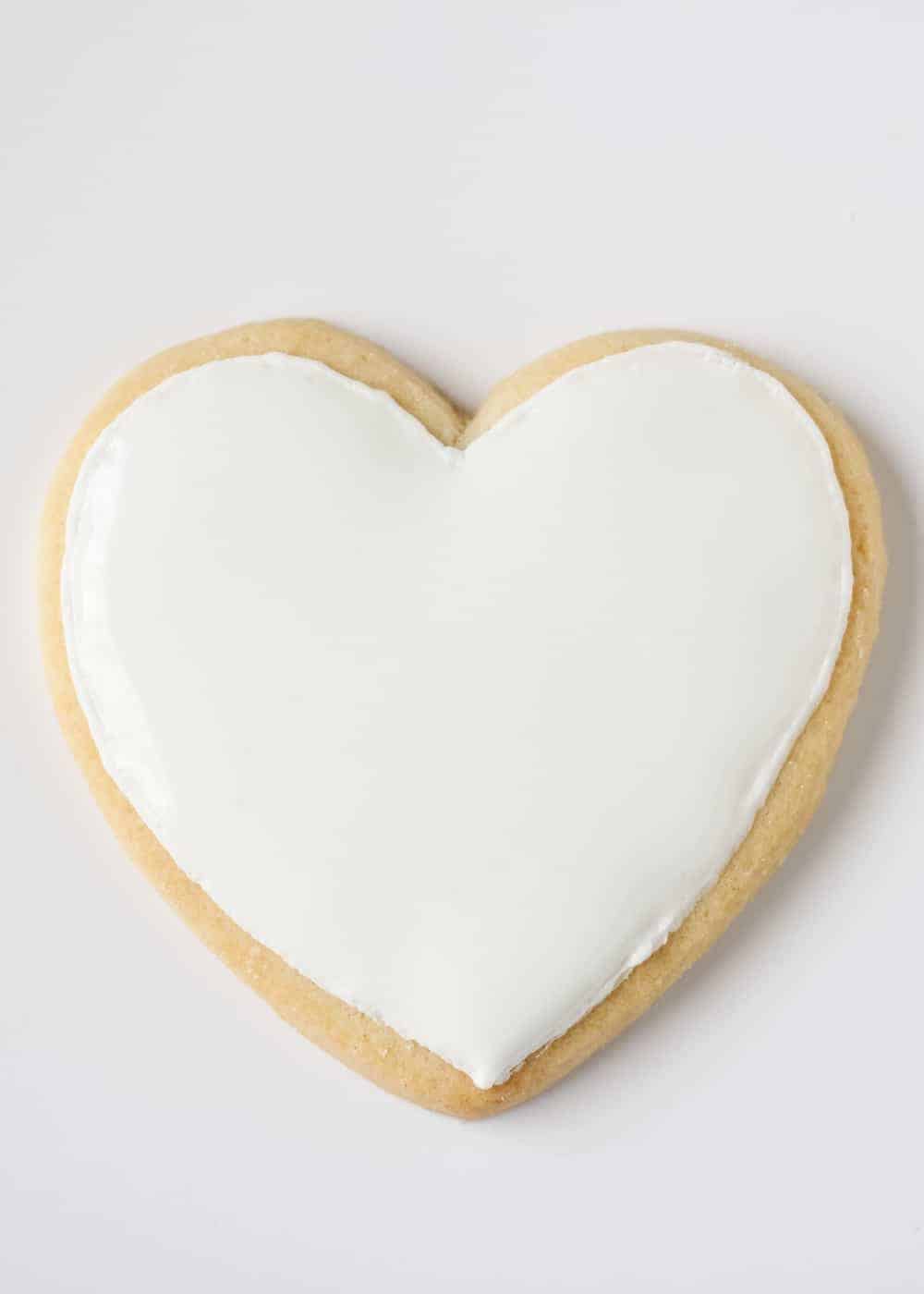 Heart shaped sugar cookie decorated with white royal icing.