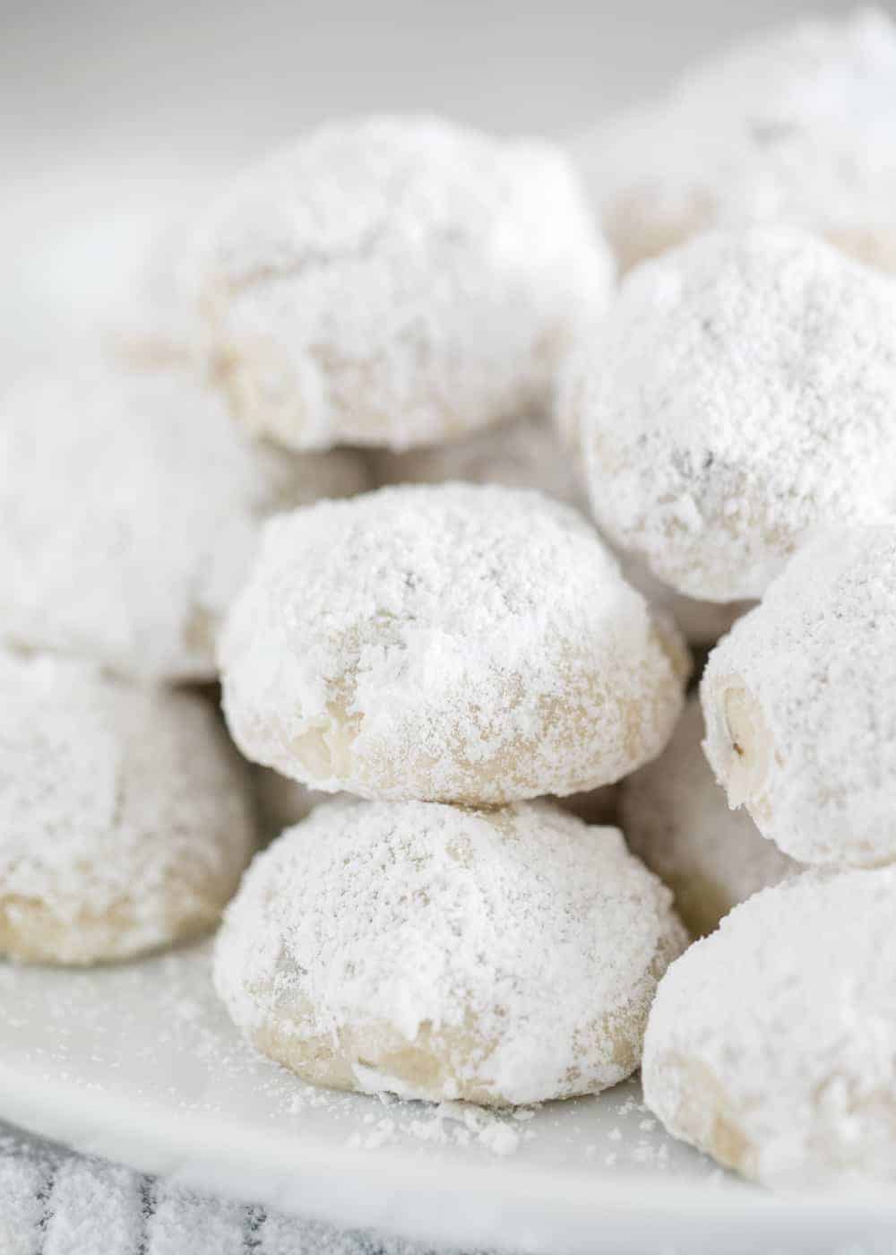 Snowball cookies stacked on white plate.