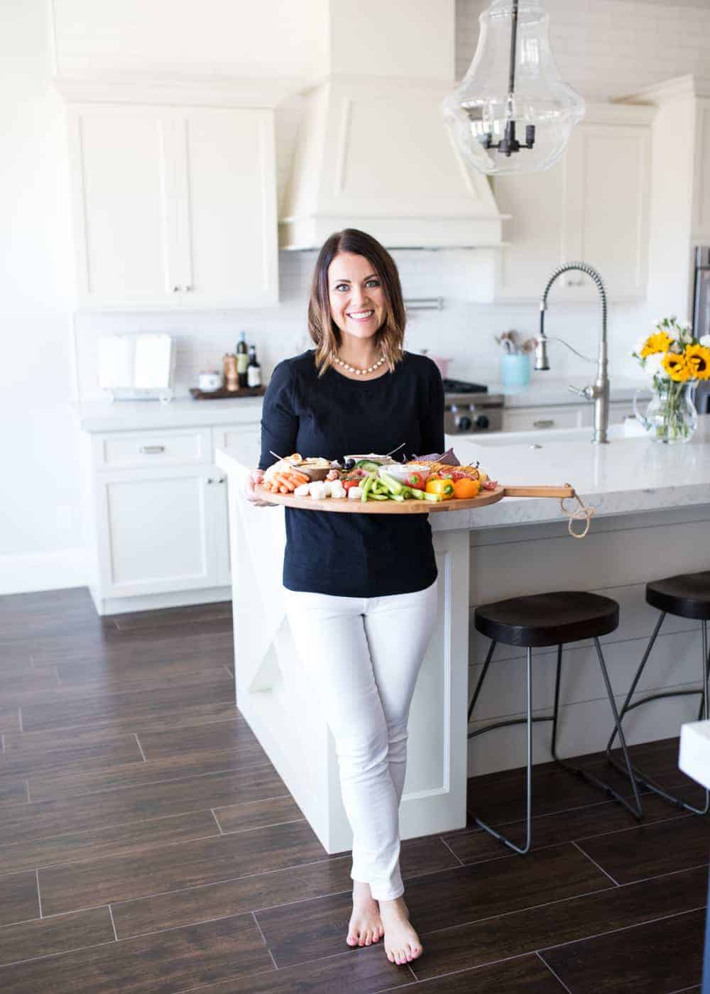 girl holding chacuterie board in kitchen