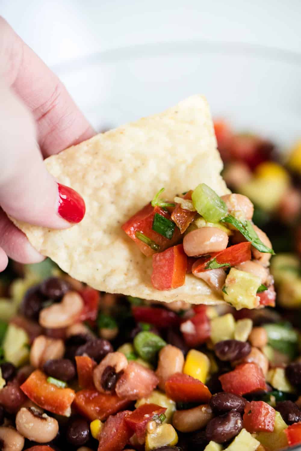 Tortilla chip being dipped in Texas caviar.