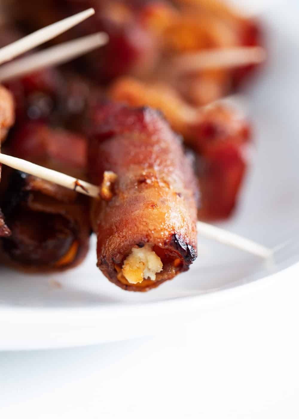 Close-up of a bacon-wrapped date on a toothpick.