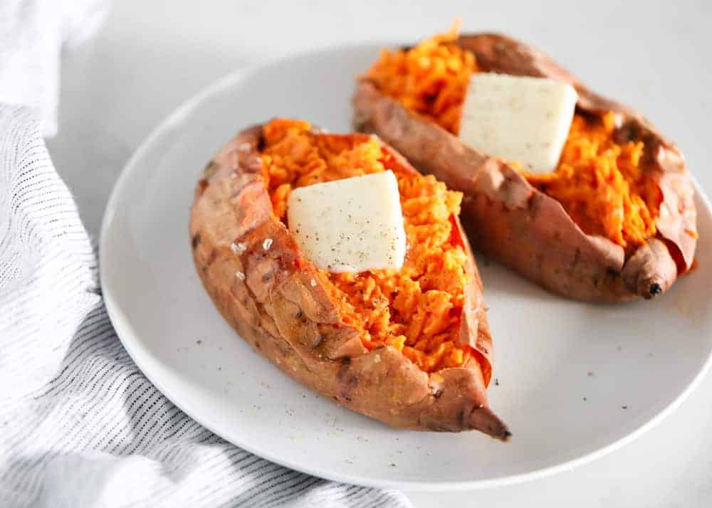 Baked sweet potatoes with butter on a white plate.