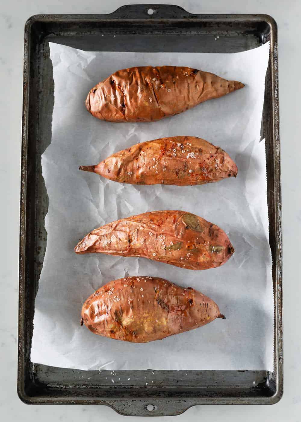 Baked sweet potatoes on a baking sheet.