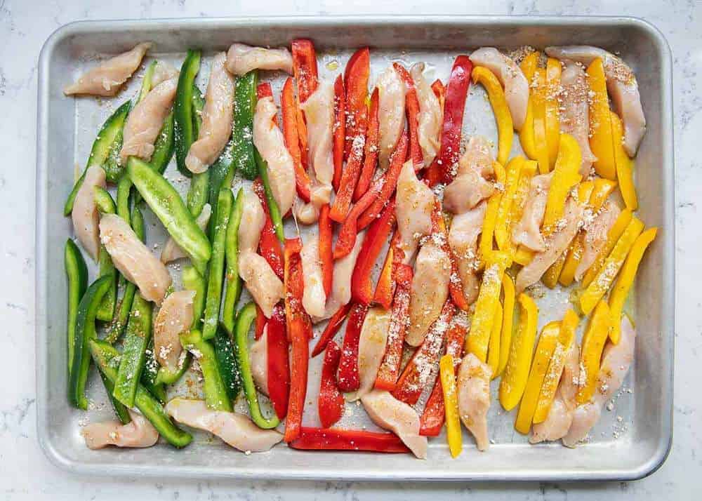 Raw chicken fajitas on sheet pan.