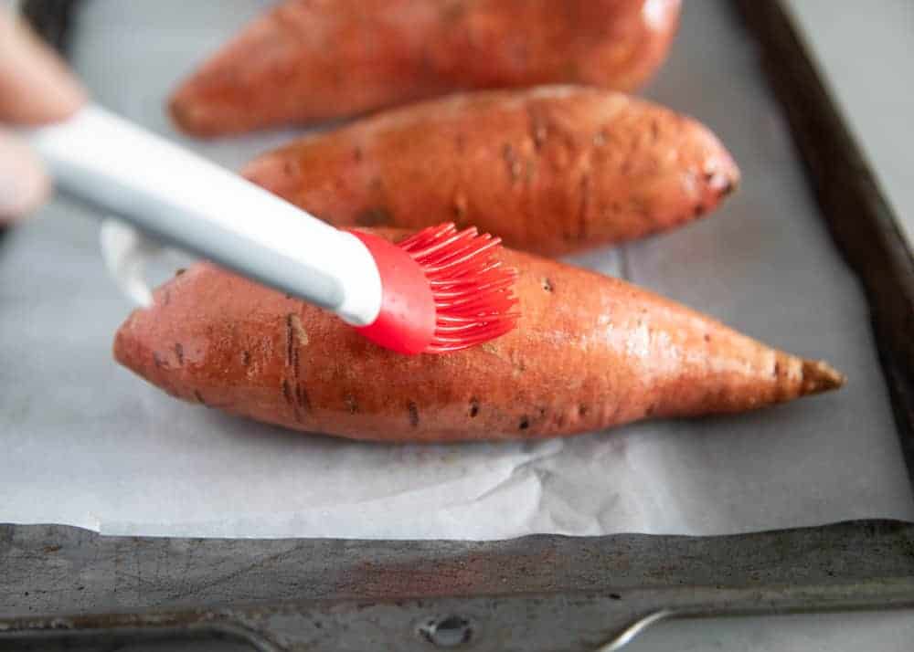 Brushing olive oil on sweet potato.