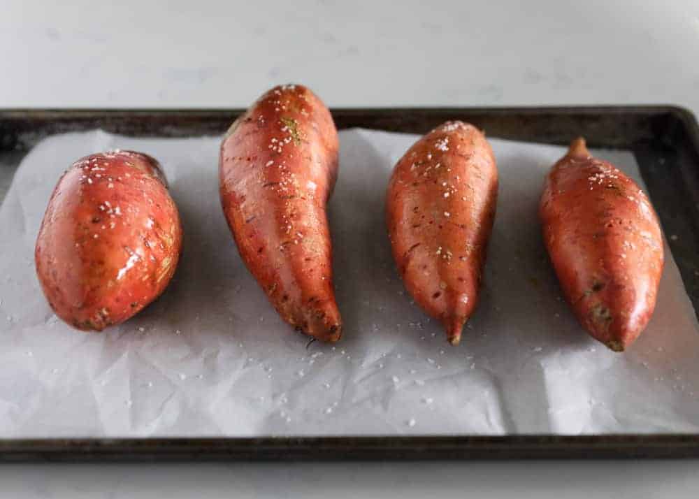 Sweet potatoes on baking sheet coated in salt.