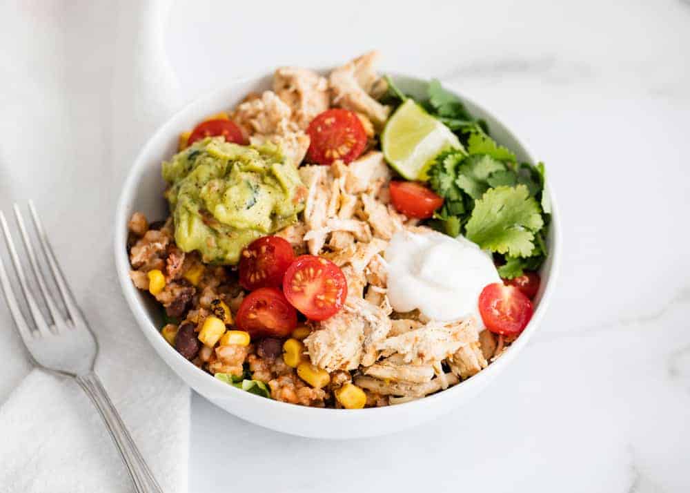 Easy instant pot chicken taco bowls that take just 5 minutes of prep. A family favorite meal idea that's perfect for busy weeknights. Just dump and go! Chicken taco bowl in white bowl.