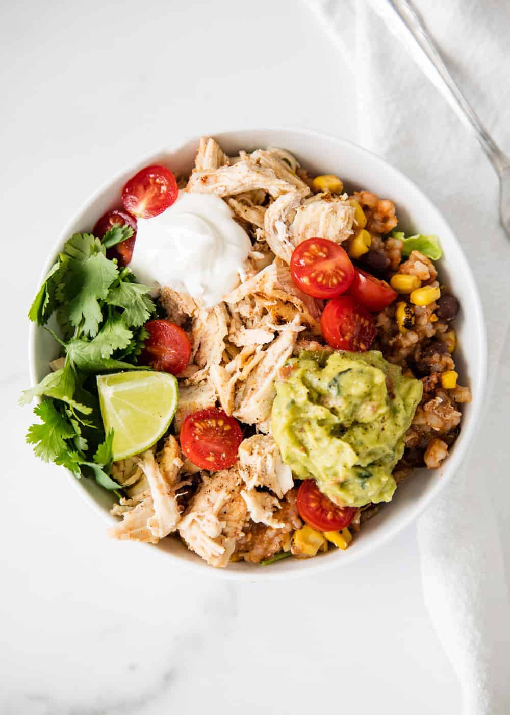 Taco bowl in a white bowl with toppings loaded on.