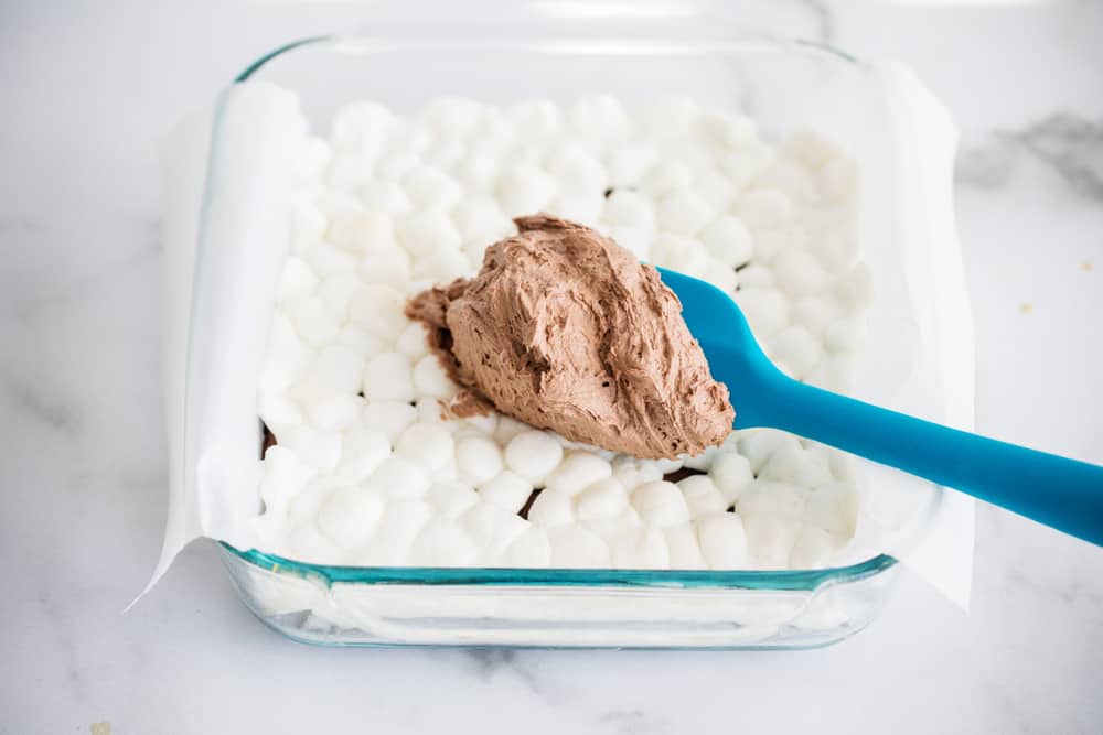 Spreading chocolate buttercream frosting over marshmallow brownies.