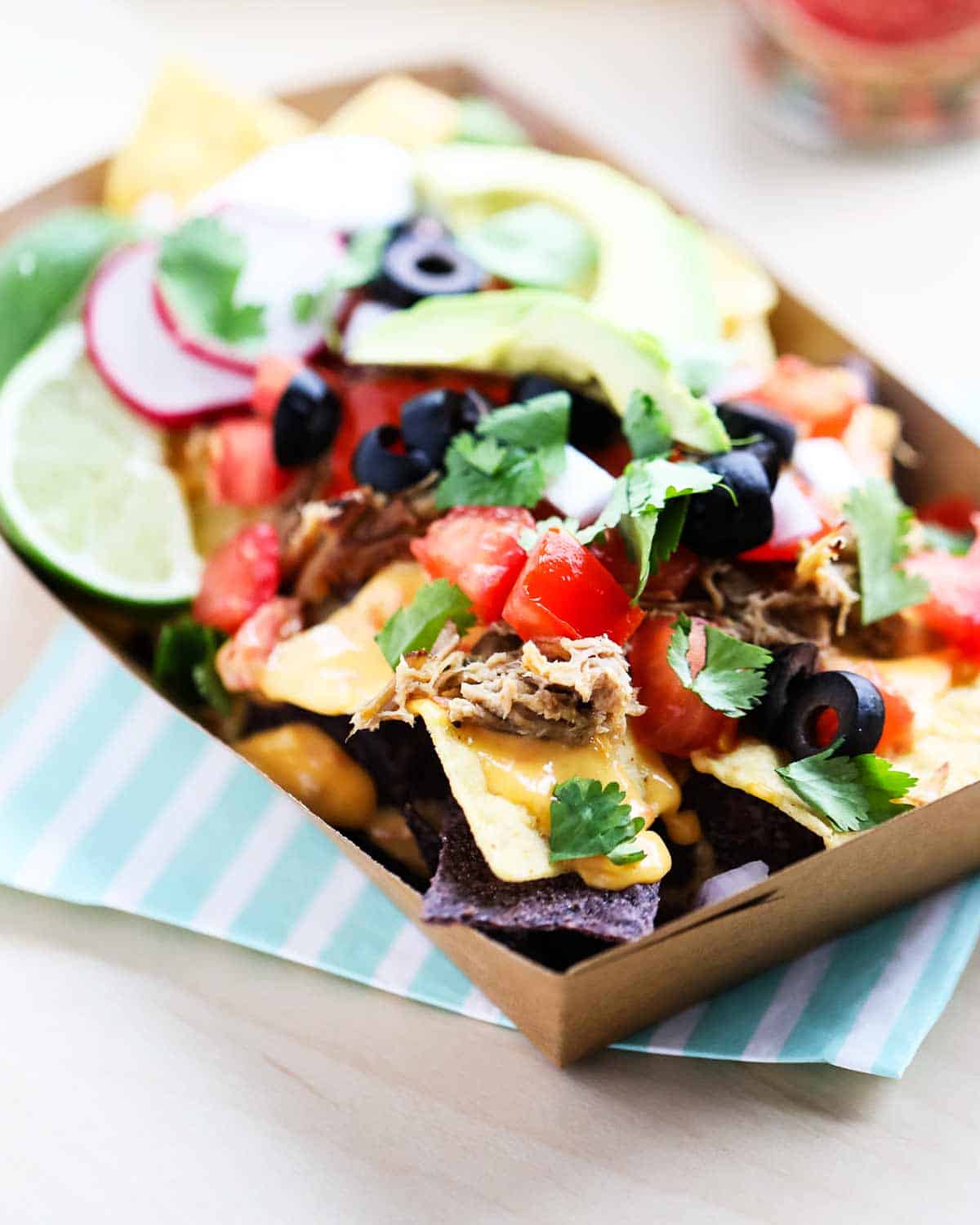 Nachos with toppings in the brown container.