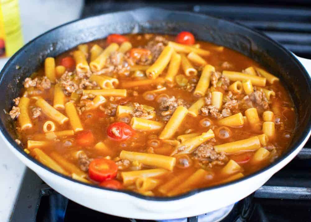 Boiling noodles in skillet for enchilada pasta.