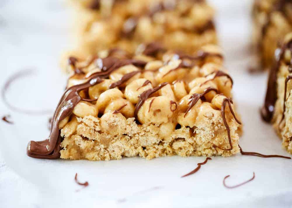 These easy no-bake peanut butter cheerio bars make the perfect snack or dessert. Only 4 ingredients and done in less than 10 minutes! Peanut butter cheerio bar with chocolate drizzled on top.
