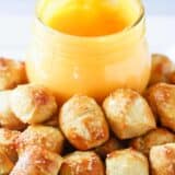 A close up of mini pretzel bites with a jar of pretzel cheese sauce