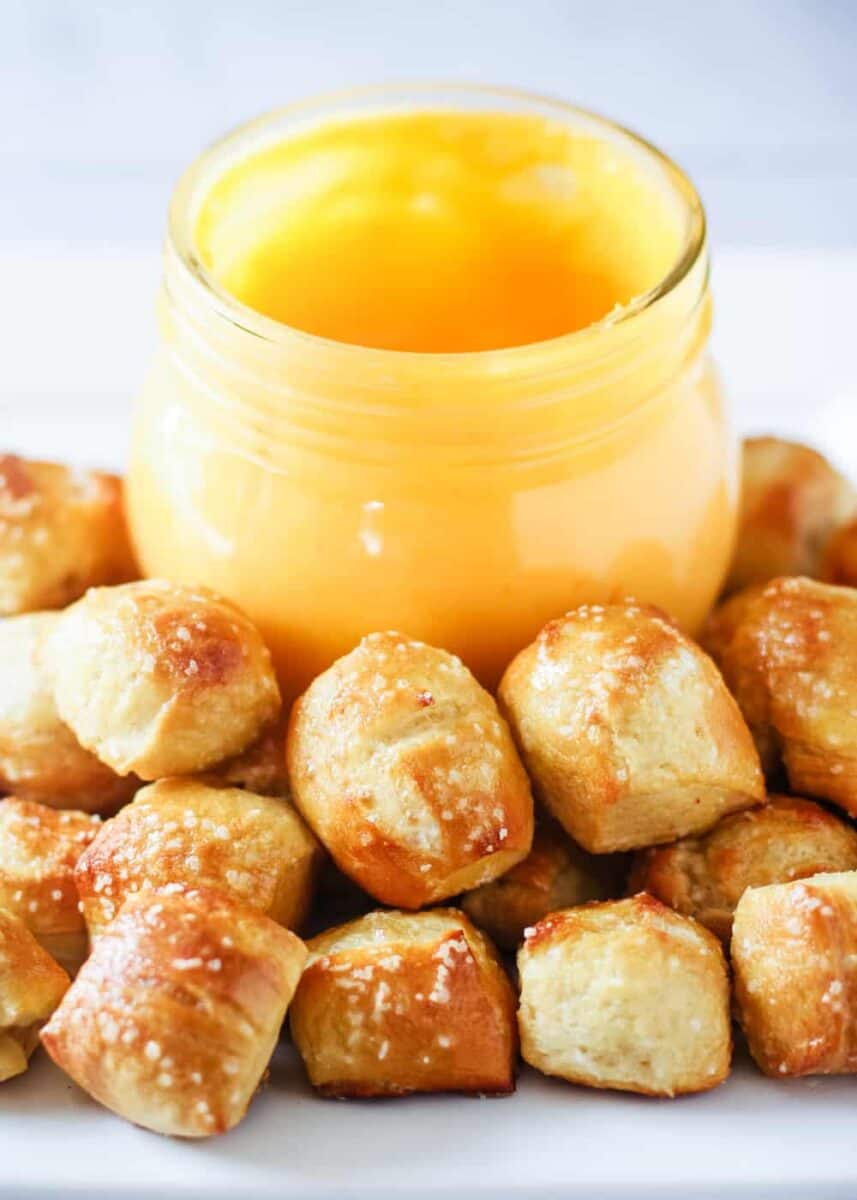 A close up of mini pretzel bites with a jar of pretzel cheese sauce. 