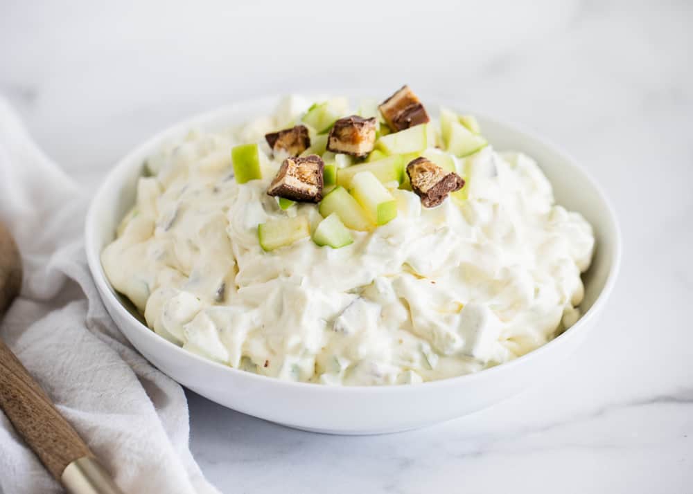 Snicker salad with apples in white bowl.