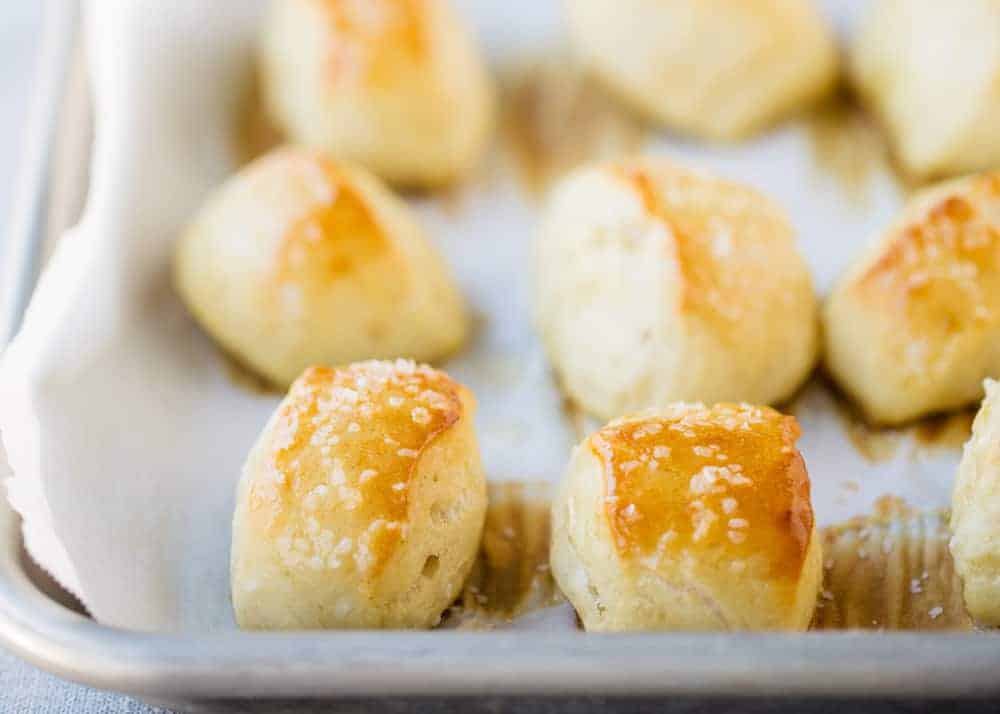 Easy homemade pretzel bites brushed with melted butter and sea salt. This easy pretzel recipe makes the perfect appetizer or snack! Always a big crowd pleaser and gone in minutes! homemade pretzel bites on a baking sheet