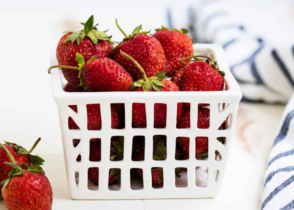 Fresh strawberries in a white basket.