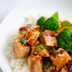 close up of teriyaki chicken in a bowl with rice and veggies