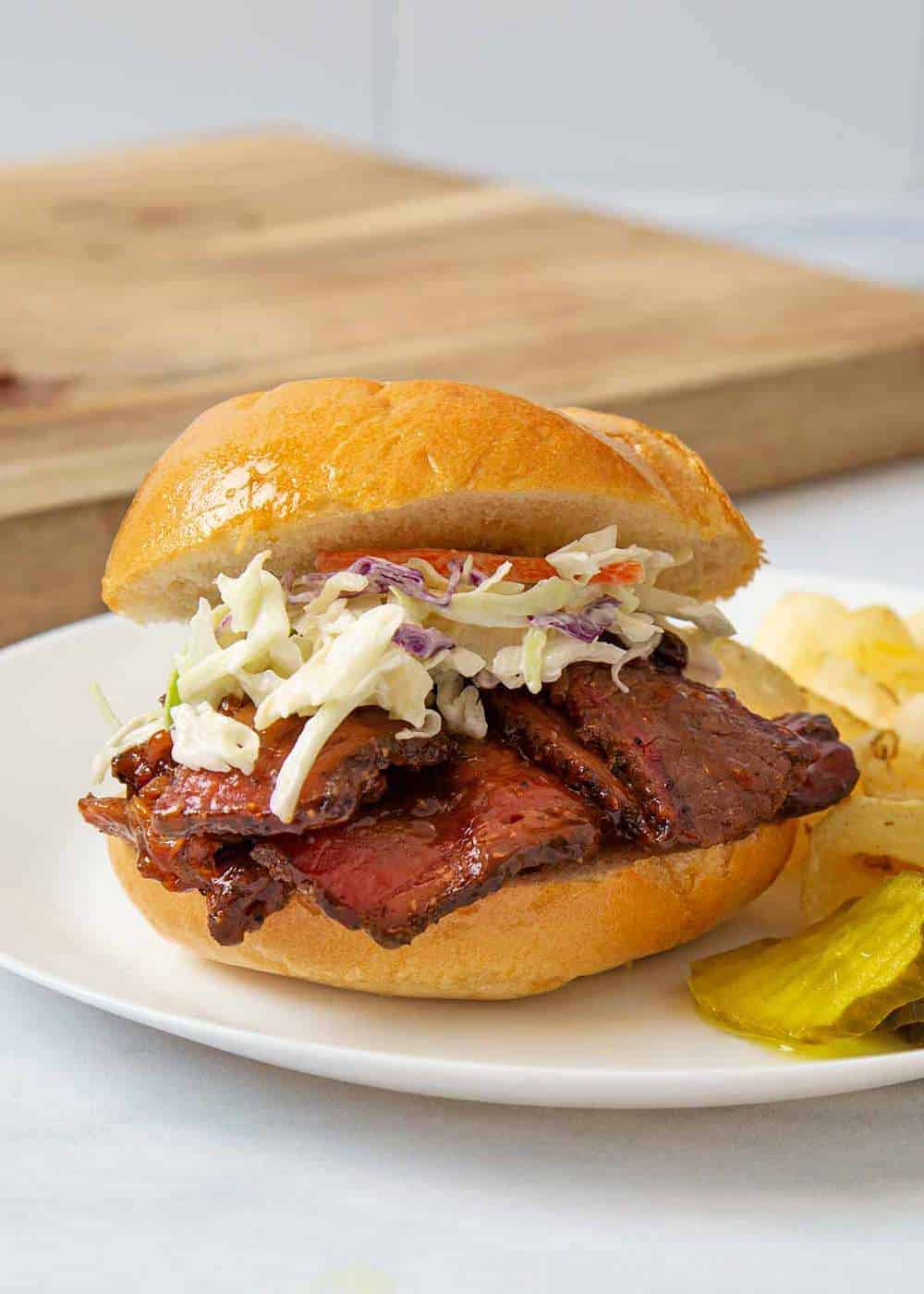 A BBQ brisket sandwich with coleslaw on a plate.