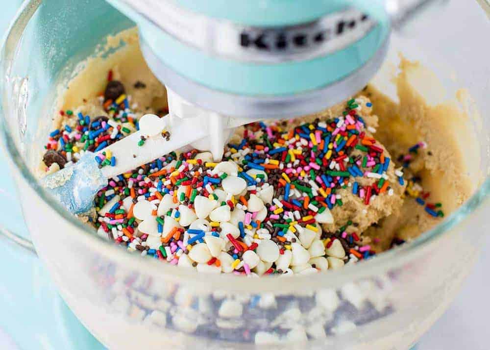 Mixing sprinkles into dough with an electric mixer.