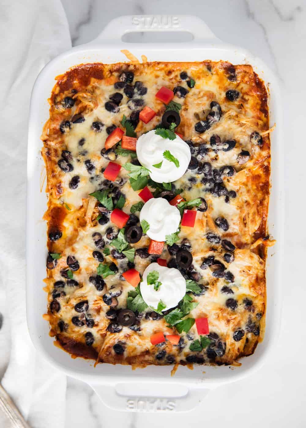 Chicken enchilada casserole in white dish.