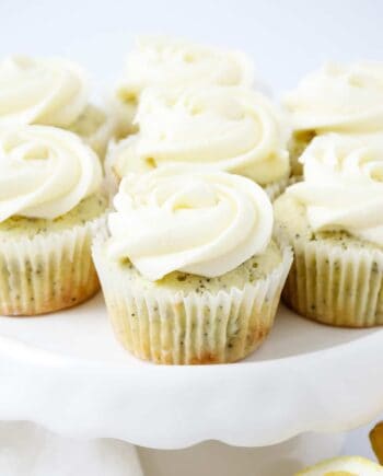 frosted lemon poppy seed cupcakes on a white cake stand